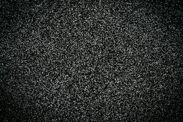 Texture of asphalt surface with small gravel stones. Dark rough road background with detailed grainy pattern. Close-up. Selective focus.