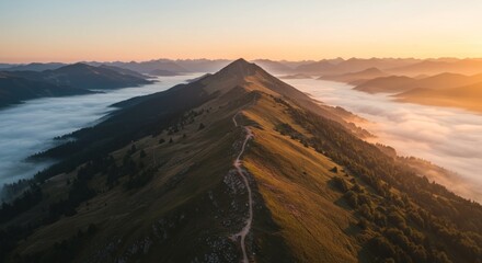 Mountain ridge with a hiking path at sunrise fog in the valley