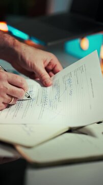Hands Signing Car Sale Agreement Document. Close-up male hands filling and signing vehicle transaction paper on desk with notebook under warm indoor lighting