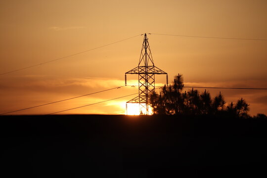 High Voltage Electric Tower Silhouette at Sunset — Energy and Nature Concept