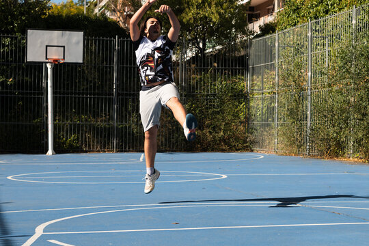 Man jumping playing basketball on outdoor court