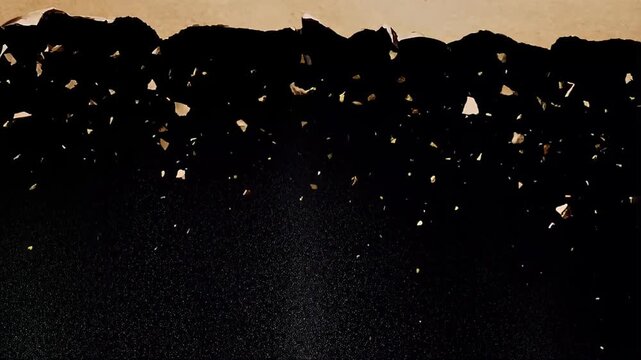 Ripped paper edge with falling torn pieces on black textured background