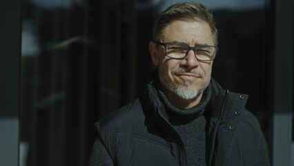 Obraz premium Portrait of middle aged man outdoor wearing pullover and vest. Middle aged male outdoor in front of wooden mountain home. Eyeglasses and gray hair. Confident look. Autumn clothing.