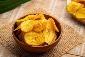 Crispy fried sliced banana with sugar,sweet banana chips in wooden bowl.