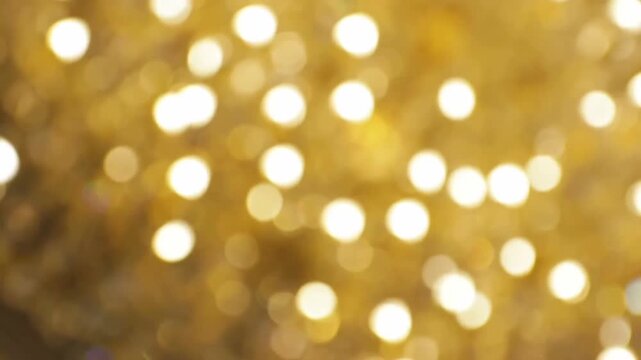 Gold rotating bokeh lights creating shimmering blur circles on soft warm glowing background
