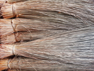 Straw broom background. Dry straw full frame. Coconut leaf broom texture. Detail of heather brooms for street cleaning. Raffia background. Cleaning utensils.