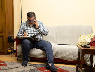 Man multitasking working from home receiving a phone call