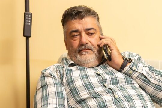 Senior man having serious phone call at home - Powered by Adobe