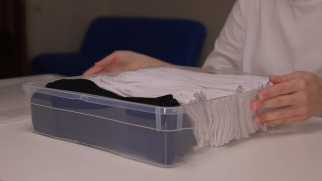 Pairing and arranging socks neatly, Carefully folding and aligning socks on clean surface, Meticulously organizing socks into perfect rows for tidy and efficient routine
