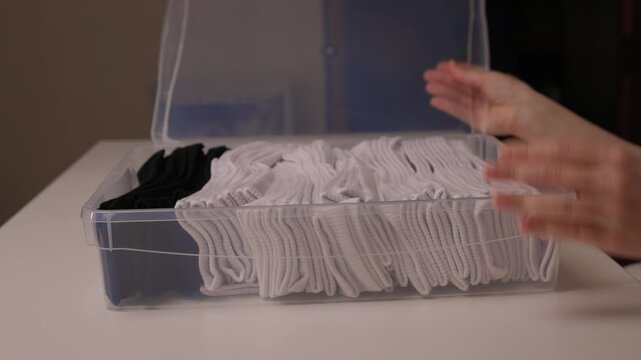 Pairing and arranging socks neatly, Carefully folding and aligning socks on clean surface, Meticulously organizing socks into perfect rows for tidy and efficient routine