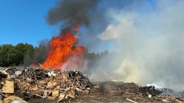 Burning garbage at landfill. A pile of wooden and construction debris is on fire. Air pollution concept