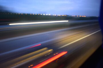 image of a blurred, motion-filled view of a highway or road, taken possibly from a moving vehicle. The scene includes streaks of red and white lights, which are characteristic of long-exposure