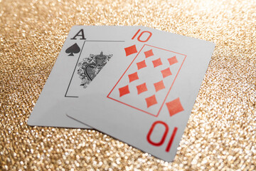 Photograph of a deck of cards forming a winning hand, for the game of Blackjack Natural, on a gold glitter background