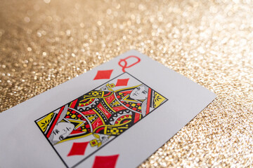 Photograph of a red queen of diamonds playing card on a gold background