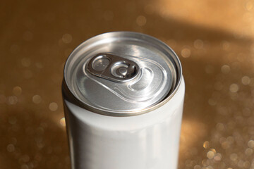 Photograph of a closed white can with a gold glitter background