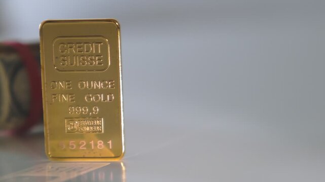 Pure one ounce gold bar from credit suisse bank with a roll of us dollar bills