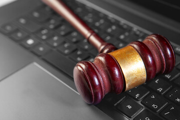 Wooden judge gavel on laptop keyboard, closeup. Law concept