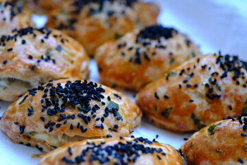 Homemade cheese and parsley pastries. Kohleria fuchsia in the background. Traditional Turkish breakfast pastries. Delicious pastries with black cumin. Ramadan iftar and sahur menu.