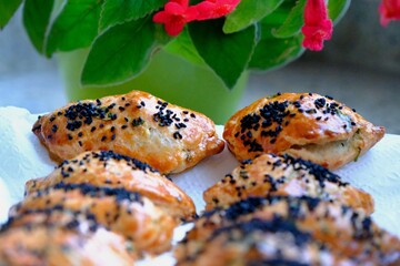 Homemade cheese and parsley pastries. Kohleria fuchsia in the background. Traditional Turkish breakfast pastries. Delicious pastries with black cumin. Ramadan iftar and sahur menu.