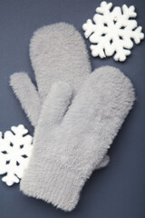 Winter grey mittens with snowflakes on dark blue background, warm mittens
