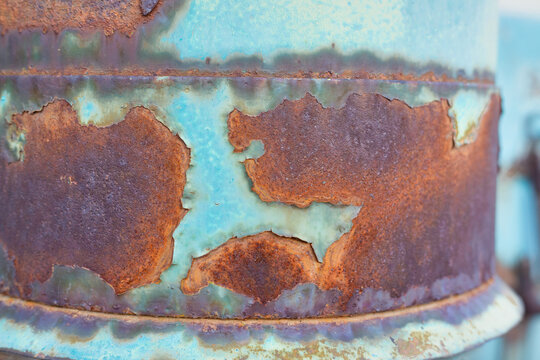 Heavily rusted metal surface with worn blue paint remnants.