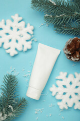 Winter skin care concept. Cosmetic moisturizer cream and snowflakes on blue background. Vertical photo