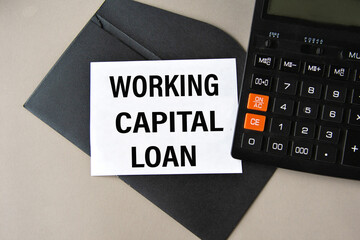 WORKING CAPITAL LOAN - words on white sheet on black envelope with calculator