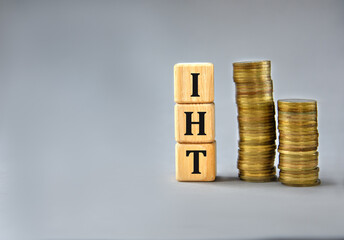IHT - acronym on wooden cubes on the background of stacks of coins