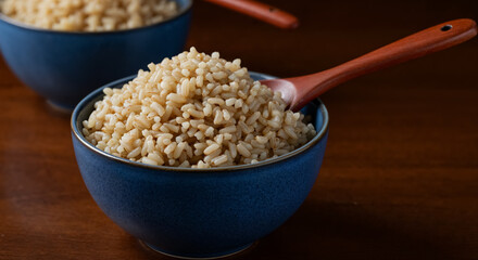 Close-Up of Cooked Brown Rice in Blue Bowls with Wooden Spoon and Warm Studio Lighting
