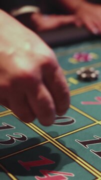 Casino table with roulette wheel in motion, with casino chips, tokens, the hand of croupier, dollar money and a group of gambling rich people playing bet on a party, blue poker table and deck of cards