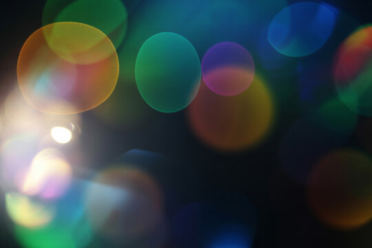 Abstract image showing out of focus multicolored lights against a dark background with lens flare