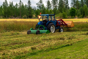 Blue farming tractor mowing grass in Stocksjo, Sweden