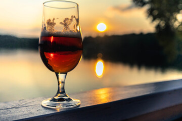 Craft beer enjoying golden sunset over serene lake
