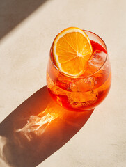 Refreshing Aperol Spritz with Orange Slice and Ice Cubes in a Glass, casting a beautiful shadow on a bright surface.