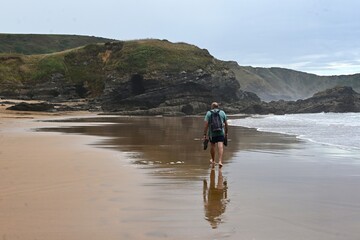 hombre paseando por la playa de verdicio, asturias, españa