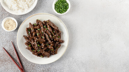 Asian-style beef stir fry with teriyaki sause, sesame seeds, green onions and rice. Top view, copy space.