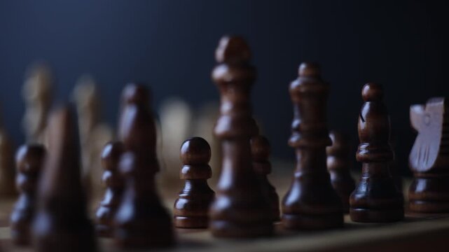 Dynamic video sequence of chess pieces positioned on a slowly rotating chessboard, symbolizing the intellectual confrontation between black and white opposing forces in strategic gameplay.