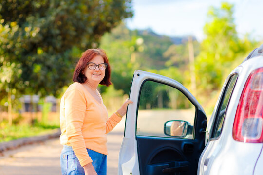 Confident mature Brazilian woman opening her car door, representing independence, freedom, and an active lifestyle after 60