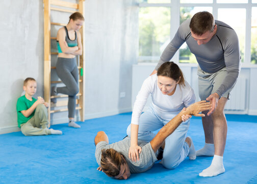 Woman student, with help of male teacher, completes neutralization of opponent, effectively defeats enemy by knockout during self-defense training