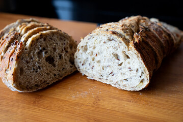 Rustic homemade bread loaf cut in half showing soft crumb texture and crispy crust. Warm tones, cozy bakery atmosphere. 