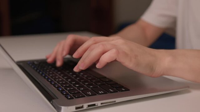 Freelancer working on computer comfortably, Hands actively typing on sleek laptop at home, Casual workspace with soft lighting and calm ambiance for remote work