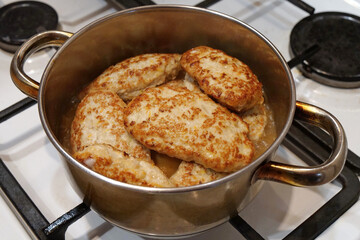 Meat patties are cooked in metal cooking pot with boiling water. Cooking