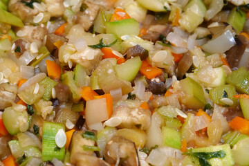 Vegetable stew is cooked on gas stove in metal pan. Vegetable ragout