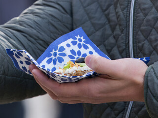 A man holding a traditional open-faced sandwich at Naplavka Farmers Market in Prague.