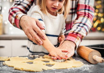 Dad and daughter cut Christmas cookie dough