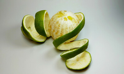 Fully Peeled Green Citrus Fruit with Spiral Skin on Clean Background, Fresh Organic Minimalist Food Art