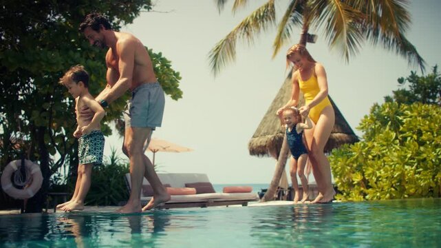 Family with young children on a relaxing tropical vacation entering an infinity pool