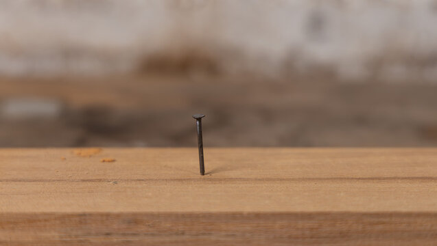 Plan serré d'un clou enfoncé dans une planche de bois.