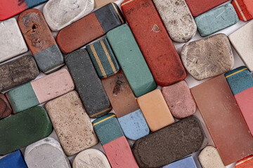 A collection of various used and worn-out erasers, flat lay photograph of a scattered collection of vintage, heavily used, and well-worn rectangular erasers