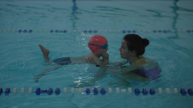 A young child learns to swim with a qualified instructor in a pool, focusing on safety and essential skills